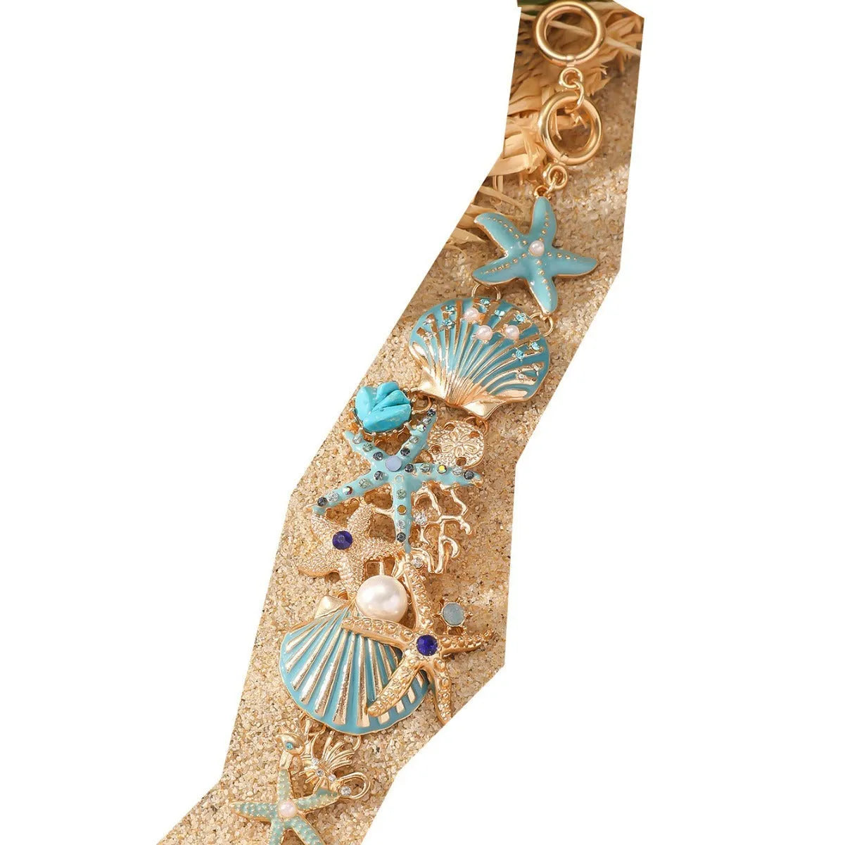 Turquoise alloy bracelet with a rhinestone boat anchor and starfish charm on a model's wrist.