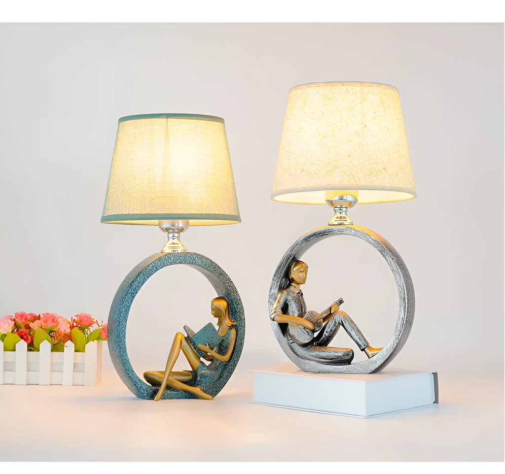Blue resin reading girl table lamp with cloth shade on a table, 20x39.8cm