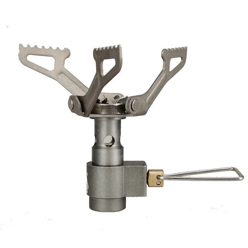 Portable camping gas stove with one-piece furnace on a rocky outdoor surface.