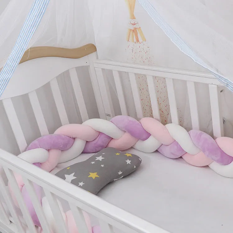 Braided knot design crib bumper in spandex velvet, shown in a light grey colour wrapped around crib slats.