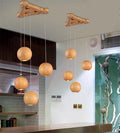 Nordic wood ball chandelier pendant light with adjustable cord, shown in a dining room setting.