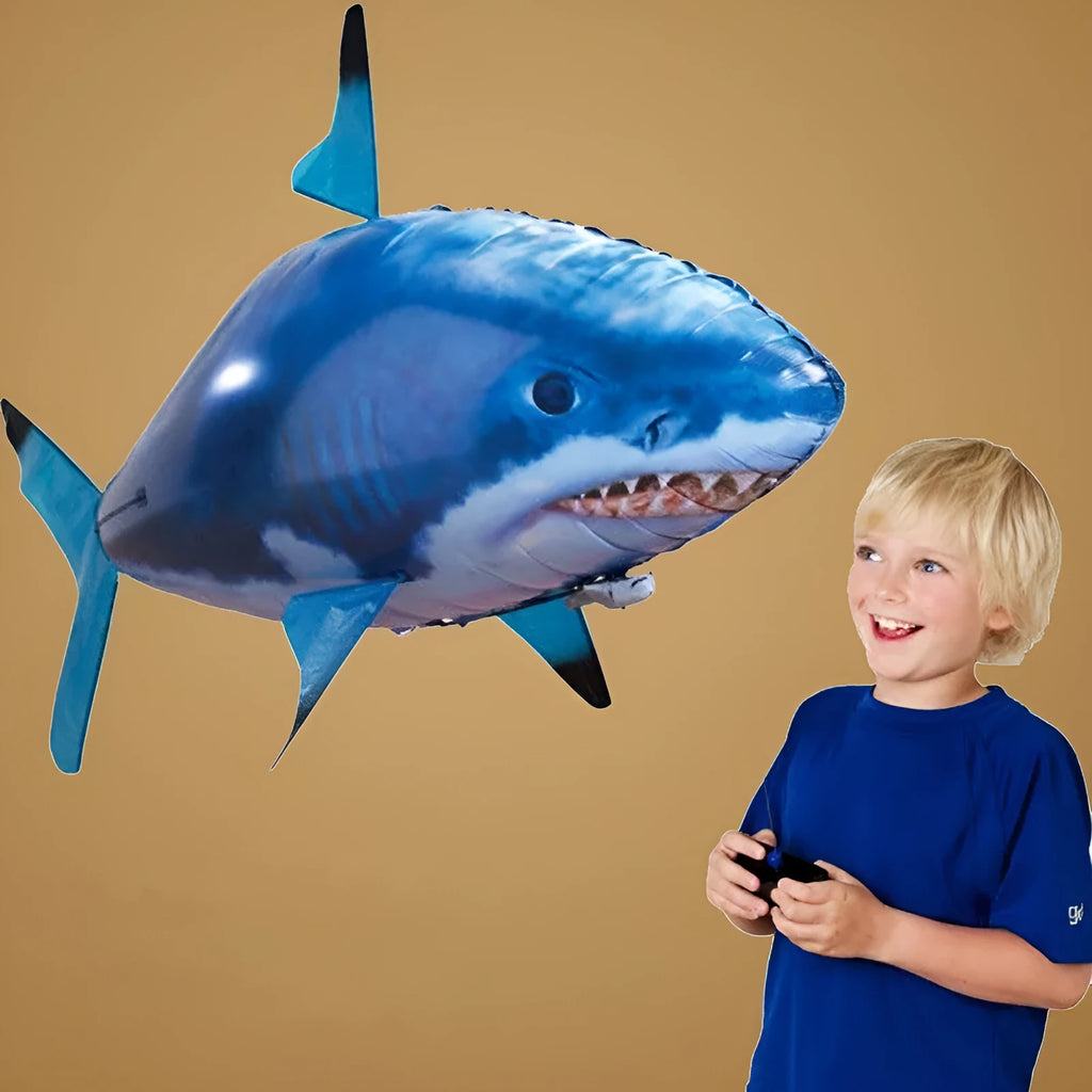 Large remote control inflatable shark balloon toy floating indoors with remote controller.