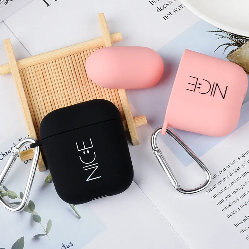 Black AirPods hard case with a smiley face design next to a pink case with a flower pattern.