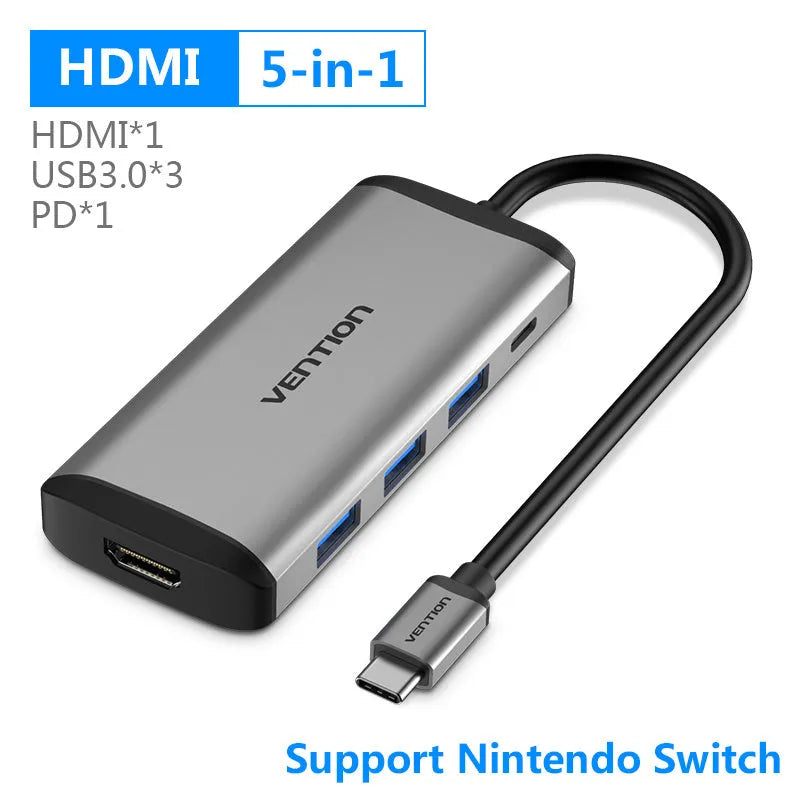 Deep grey USB-C multiport hub with HDMI, USB 3.0, Ethernet, and card reader ports on a desk.