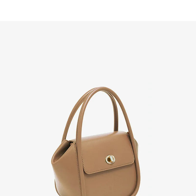 Women's winged leather handbag with cross-body strap in blue, showing latch closure and buckle detail.