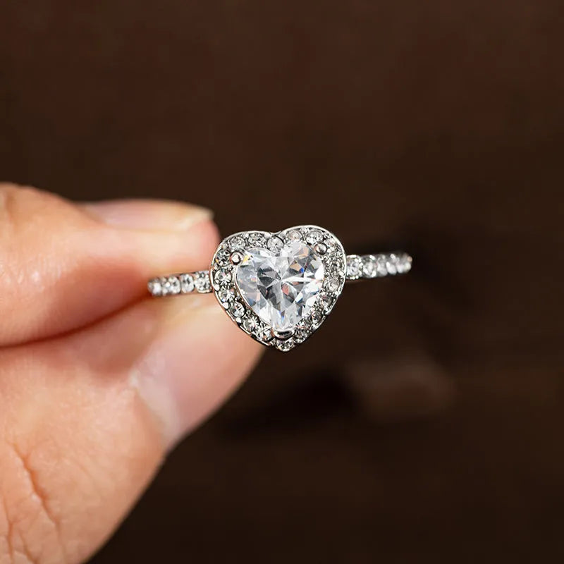 Women's heart-shaped crystal wedding ring in rose gold or silver on a white background.