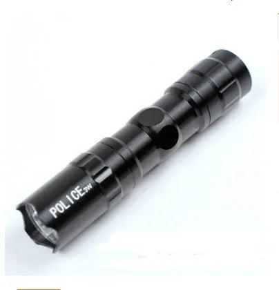 Small black aluminium LED flashlight showing compact size next to a AA battery for scale.