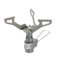 Portable camping gas stove with one-piece furnace on a rocky outdoor surface.
