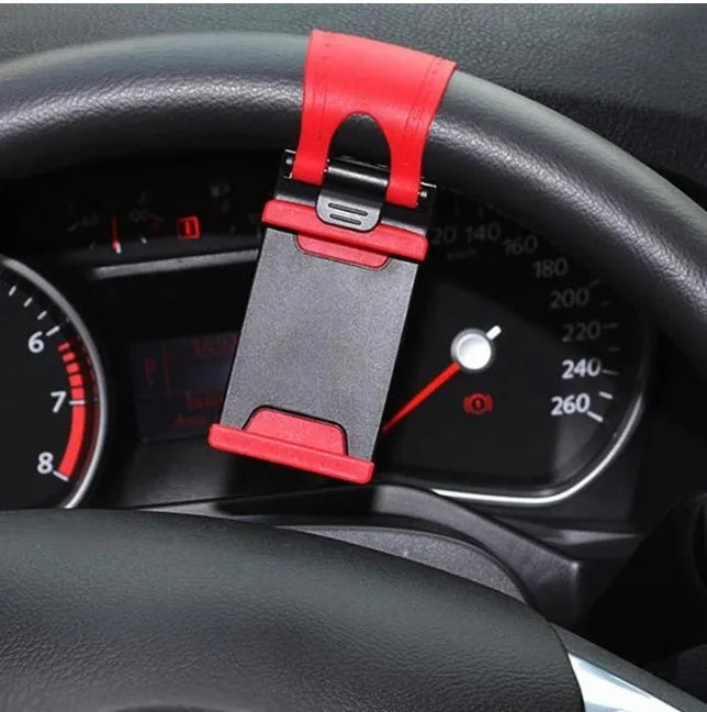 Black steering wheel phone mount holder clipped to a car wheel, holding a large smartphone.