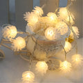 Warm white LED pine cone light string powered by AA batteries, shown in a 10-light or 20-light option for decorative use.