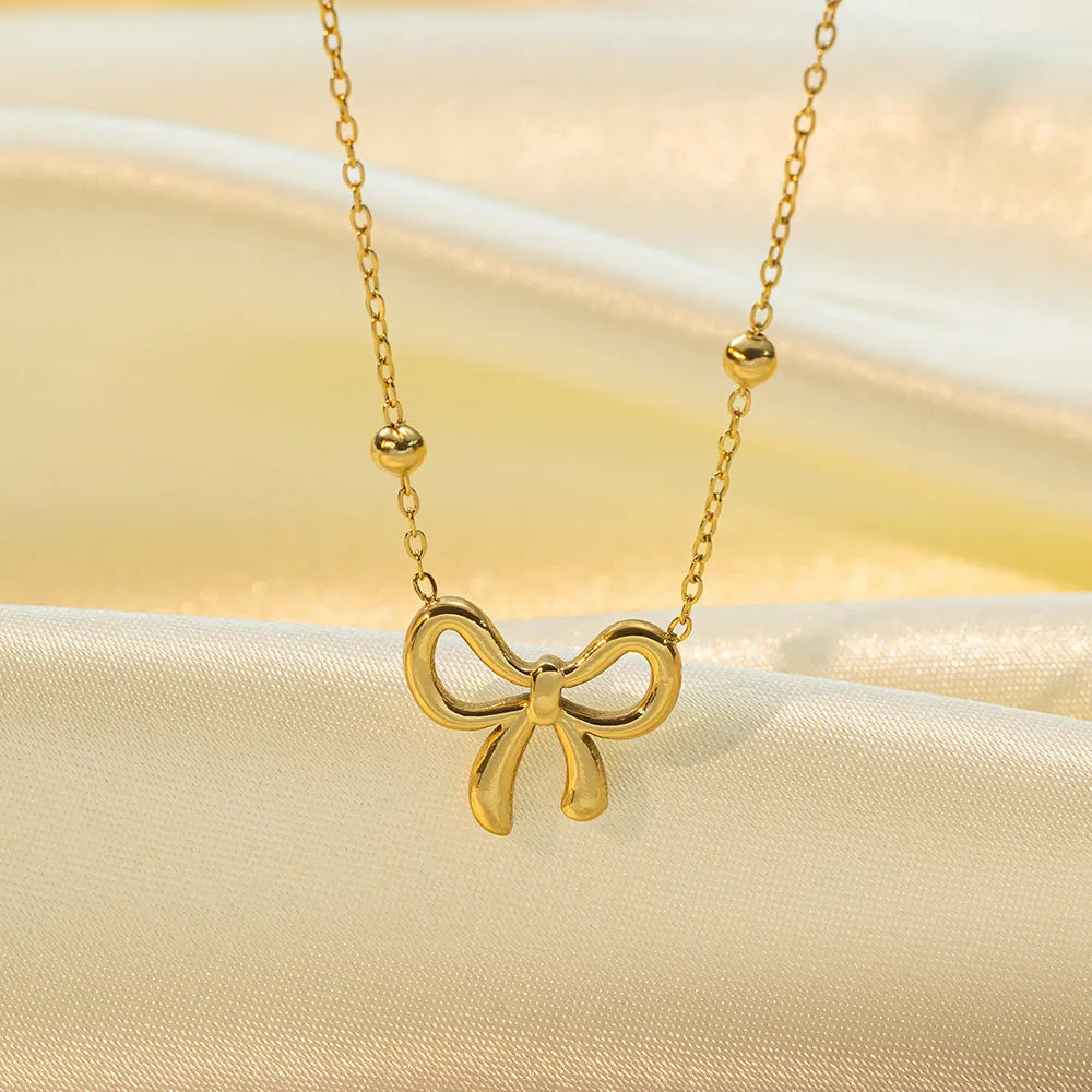 Gold electroplated bow necklace with adjustable cross chain for women