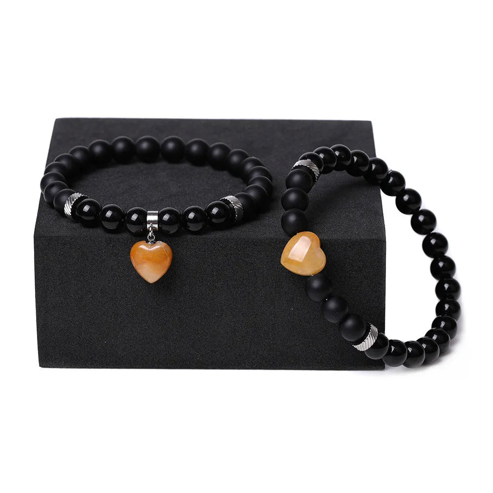 A pair of natural stone heart bracelets for couples on a background, showing geometric polished gemstone designs.