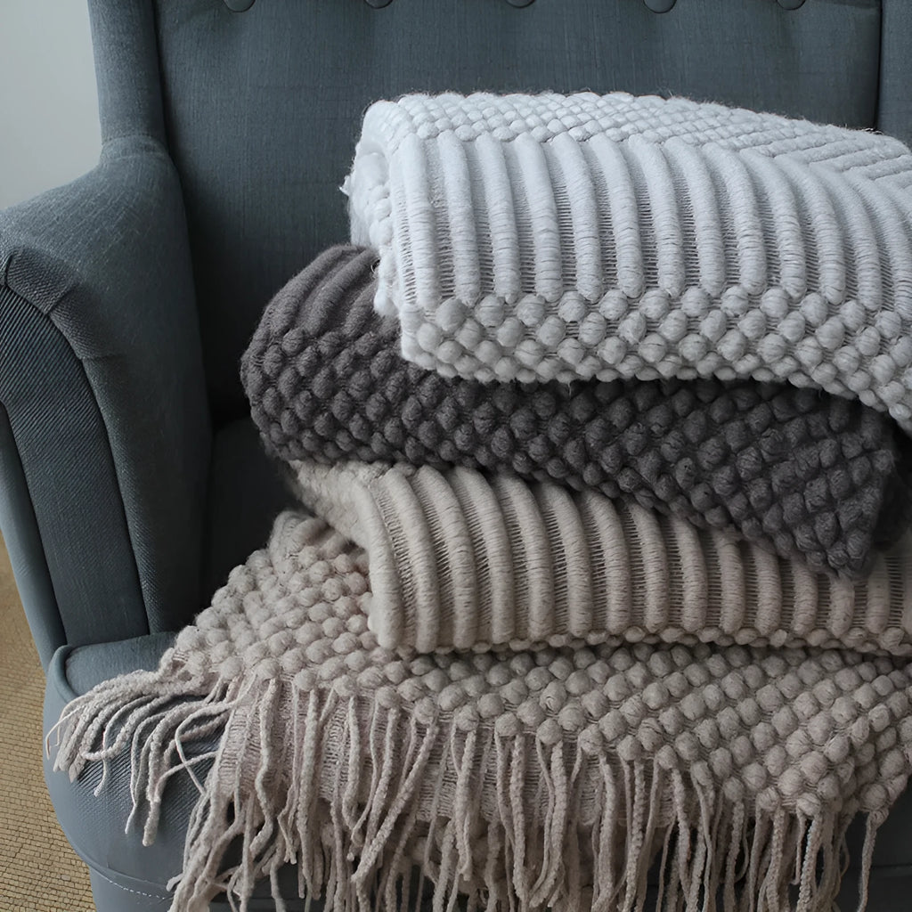 Small light grey polyester fibre blanket measuring 127 by 170 centimetres, folded on a sofa.