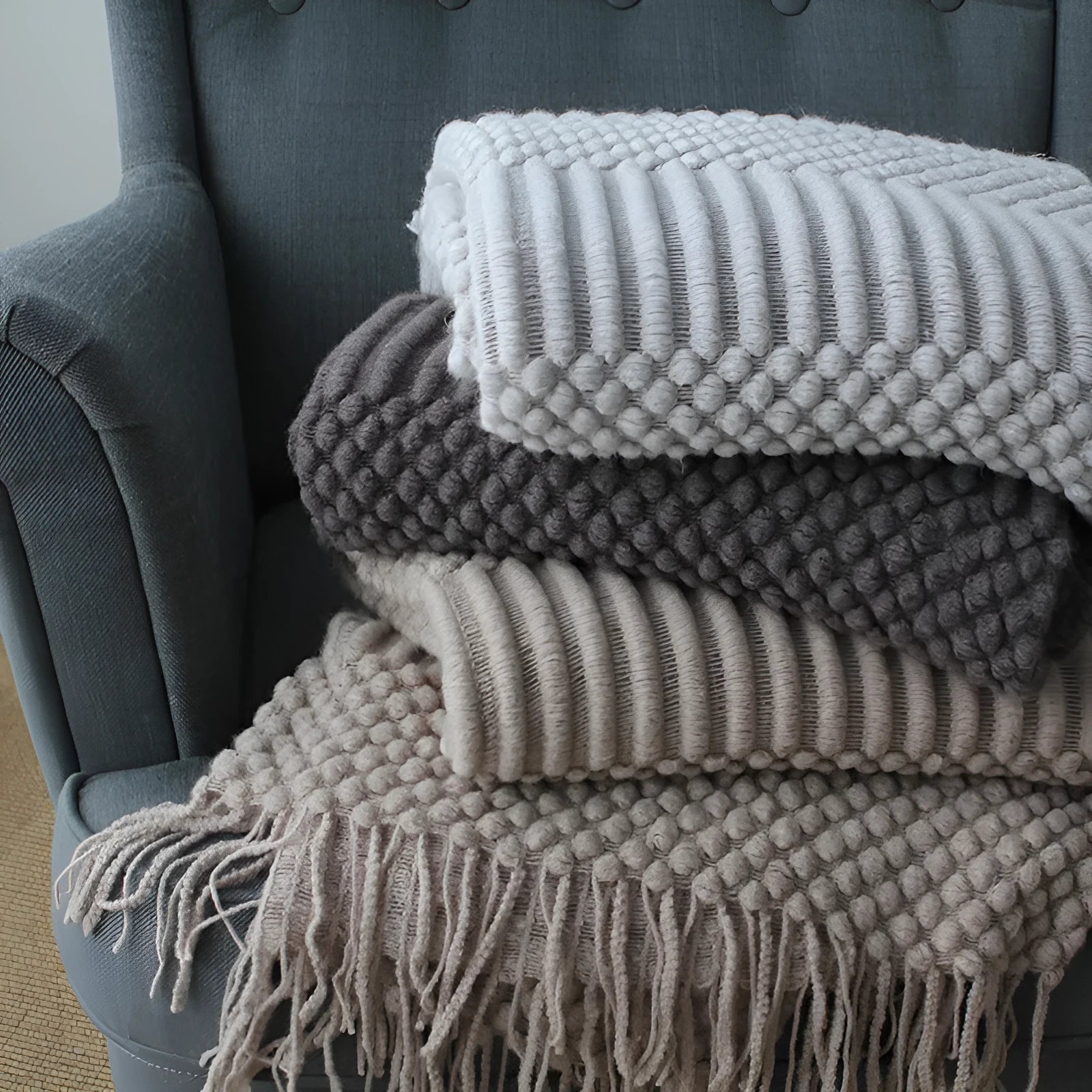 Small light grey polyester fibre blanket measuring 127 by 170 centimetres, folded on a sofa.