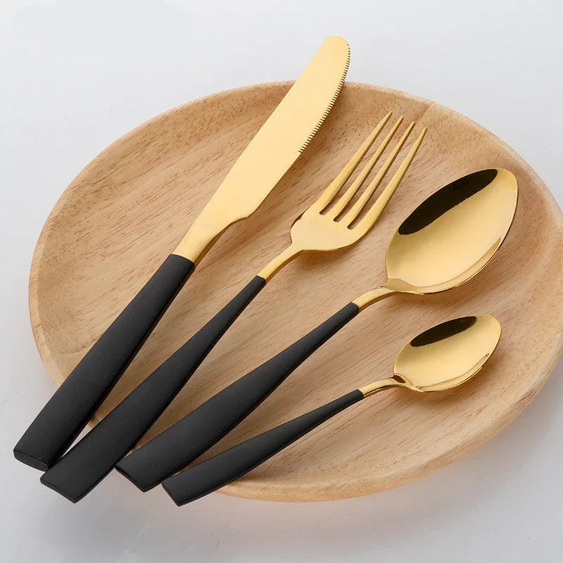 Black stainless steel four-piece cutlery set with mirror-polished finish on a plain surface