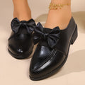 Women's brown leather-look loafers with a large bow detail on the front.