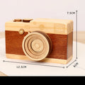 Small wooden camera-shaped music box with a rotating mechanism on a natural pine wood finish.