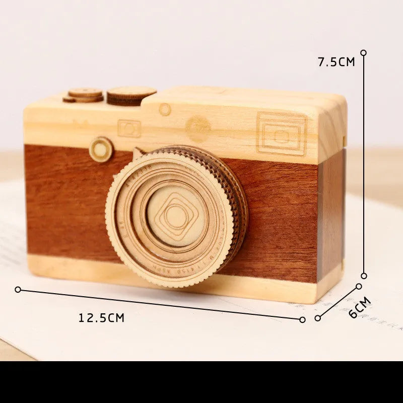 Small wooden camera-shaped music box with a rotating mechanism on a natural pine wood finish.
