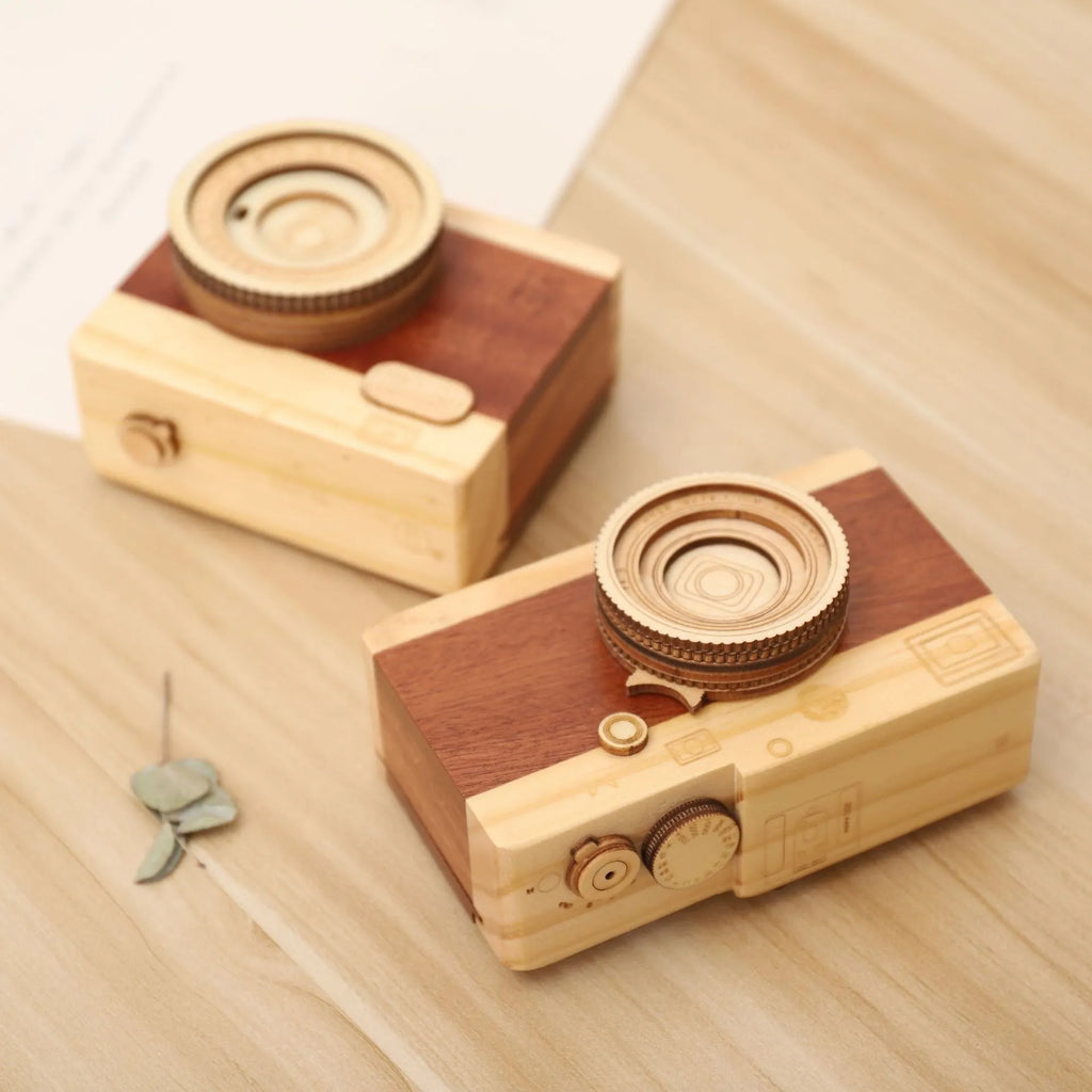 Small wooden camera-shaped music box with a rotating mechanism on a natural pine wood finish.