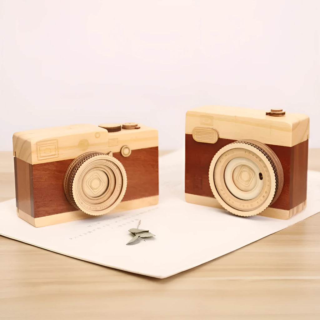 Small wooden camera-shaped music box with a rotating mechanism on a natural pine wood finish.