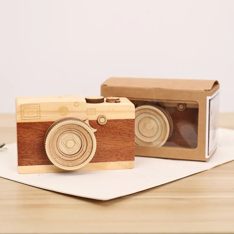 Small wooden camera-shaped music box with a rotating mechanism on a natural pine wood finish.