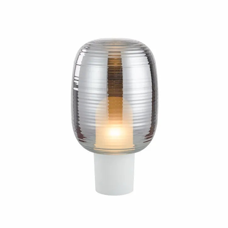 Modern glass table lamp in cognac colour with a push-button switch on a wooden surface.