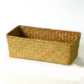 Natural straw desk storage box with lid in brown, shown on a wooden table.