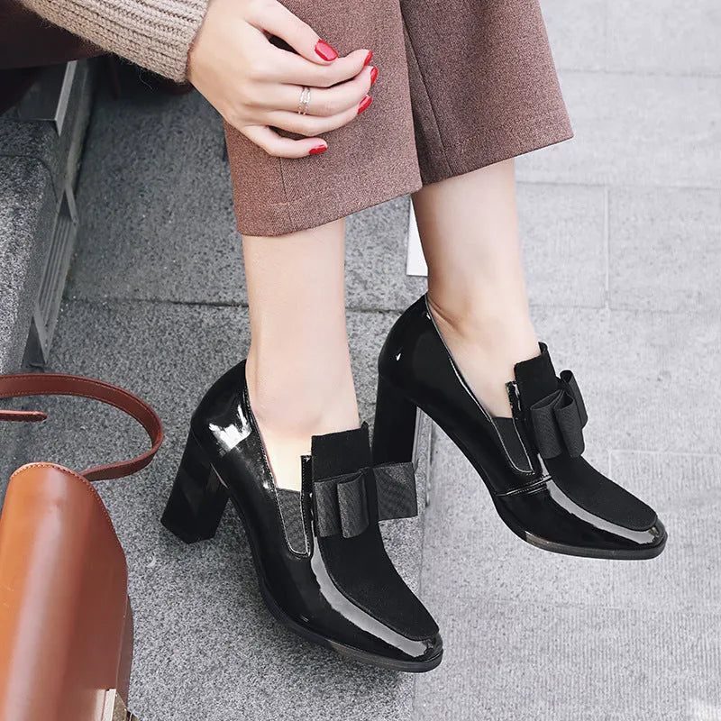 Black leather women's high heel shoes with a thick block heel and square toe, showing patent leather finish.