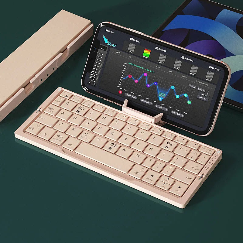 Silver white mini aluminium folding Bluetooth keyboard open next to a smartphone on its integrated stand.
