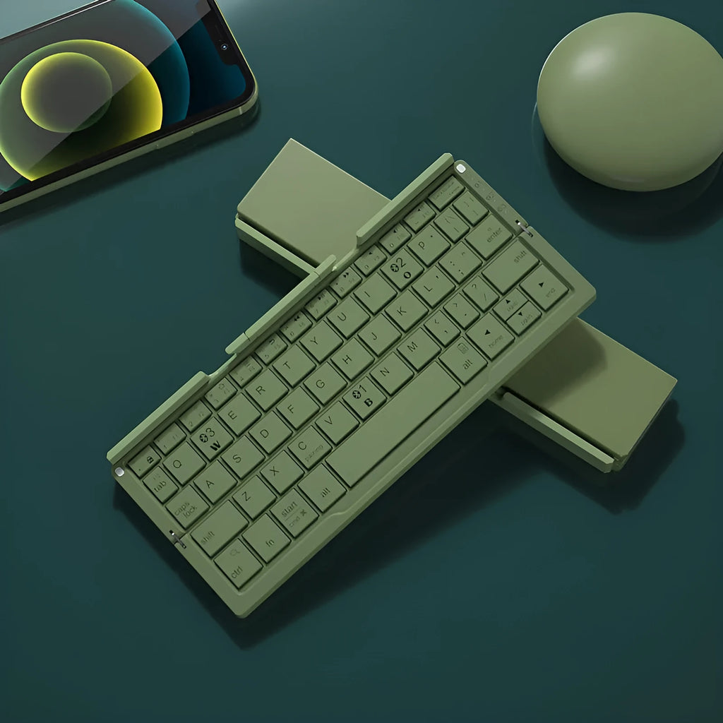 Silver white mini aluminium folding Bluetooth keyboard open next to a smartphone on its integrated stand.