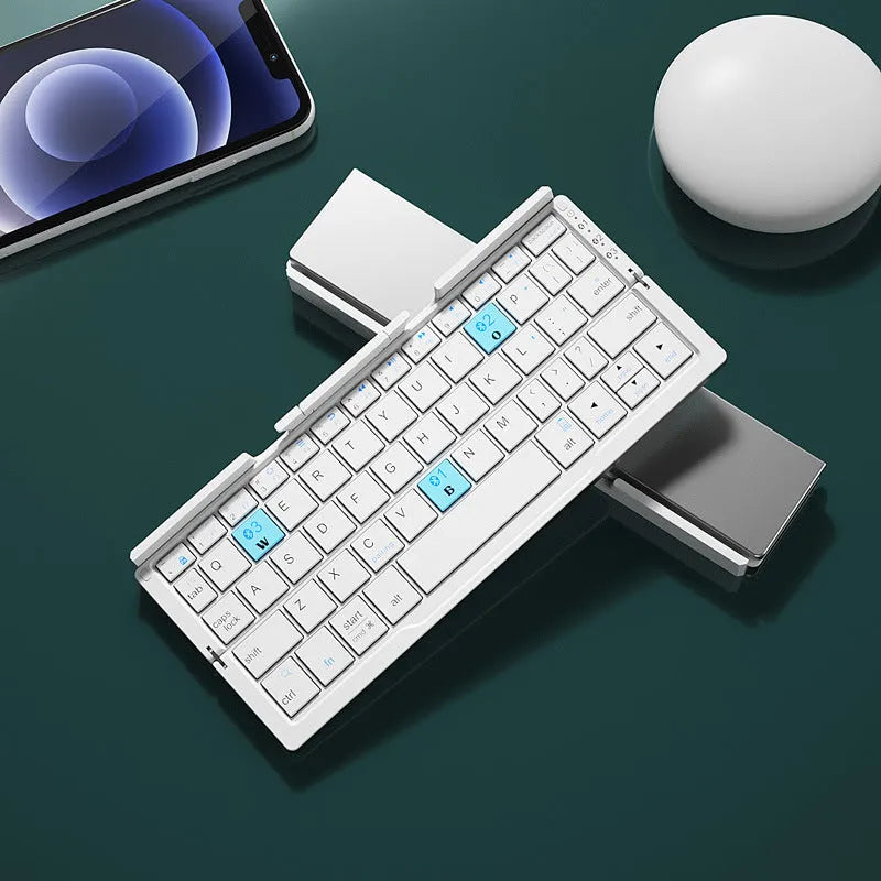 Silver white mini aluminium folding Bluetooth keyboard open next to a smartphone on its integrated stand.