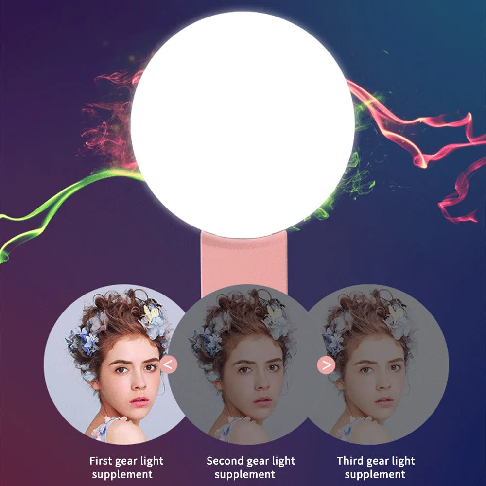 A small, round white clip-on LED fill light attached to a mobile phone for taking selfies.