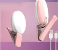 A small, round white clip-on LED fill light attached to a mobile phone for taking selfies.