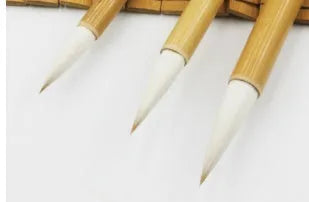 Three Chinese calligraphy brushes with bamboo handles and wool bristles shown in large, medium, and small sizes.