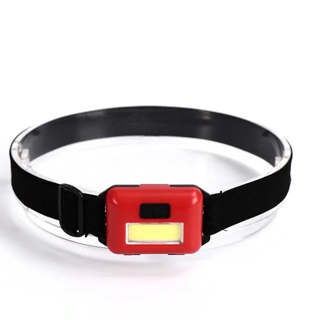 Compact black outdoor LED headlight with adjustable polyester headband, shown in use.