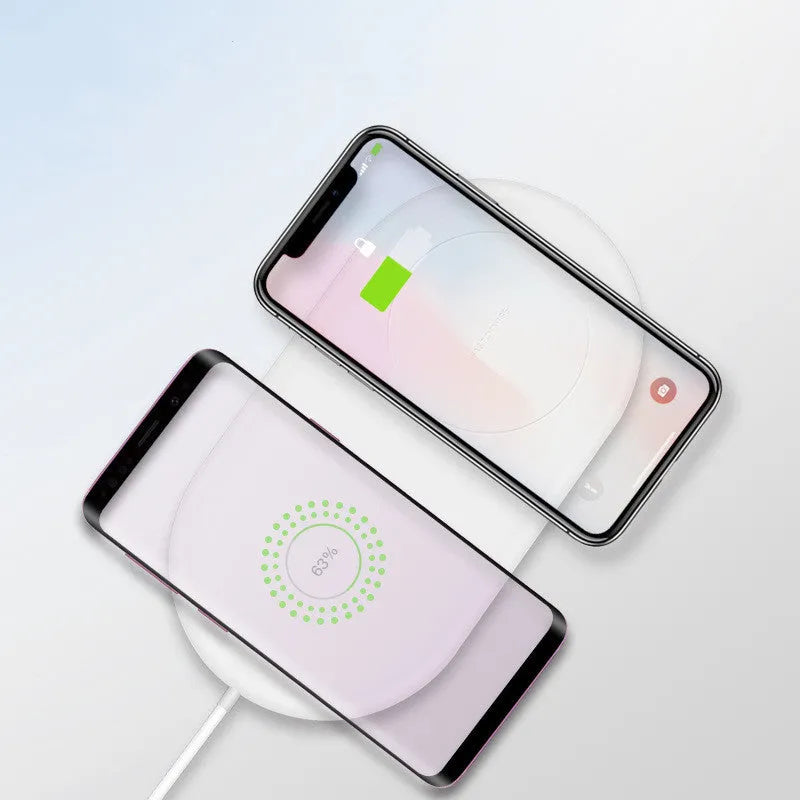 White circular wireless charger showing two smartphones charging simultaneously on its surface