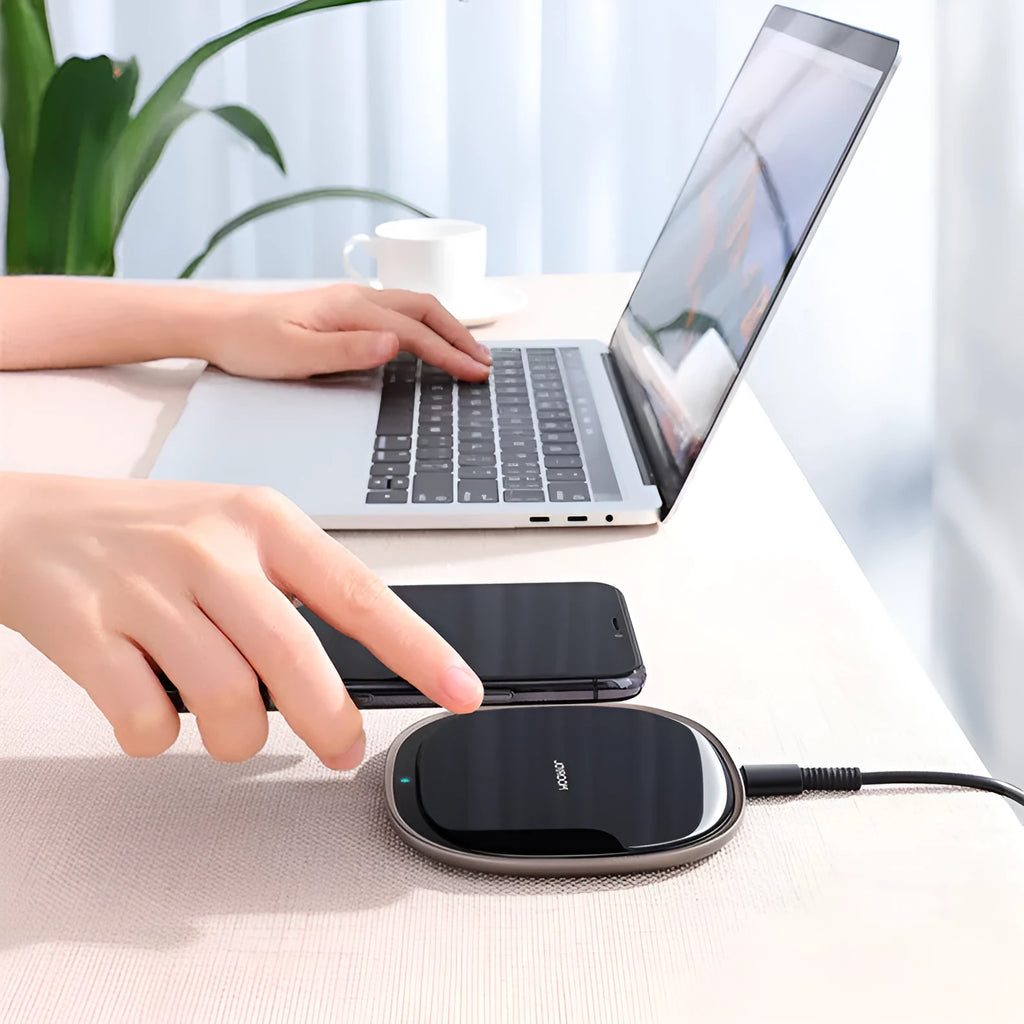 Black 15W square wireless charging pad with a glass top on a desk