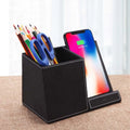 Black leather wireless charging station with pen holder slots showing phone charging on surface