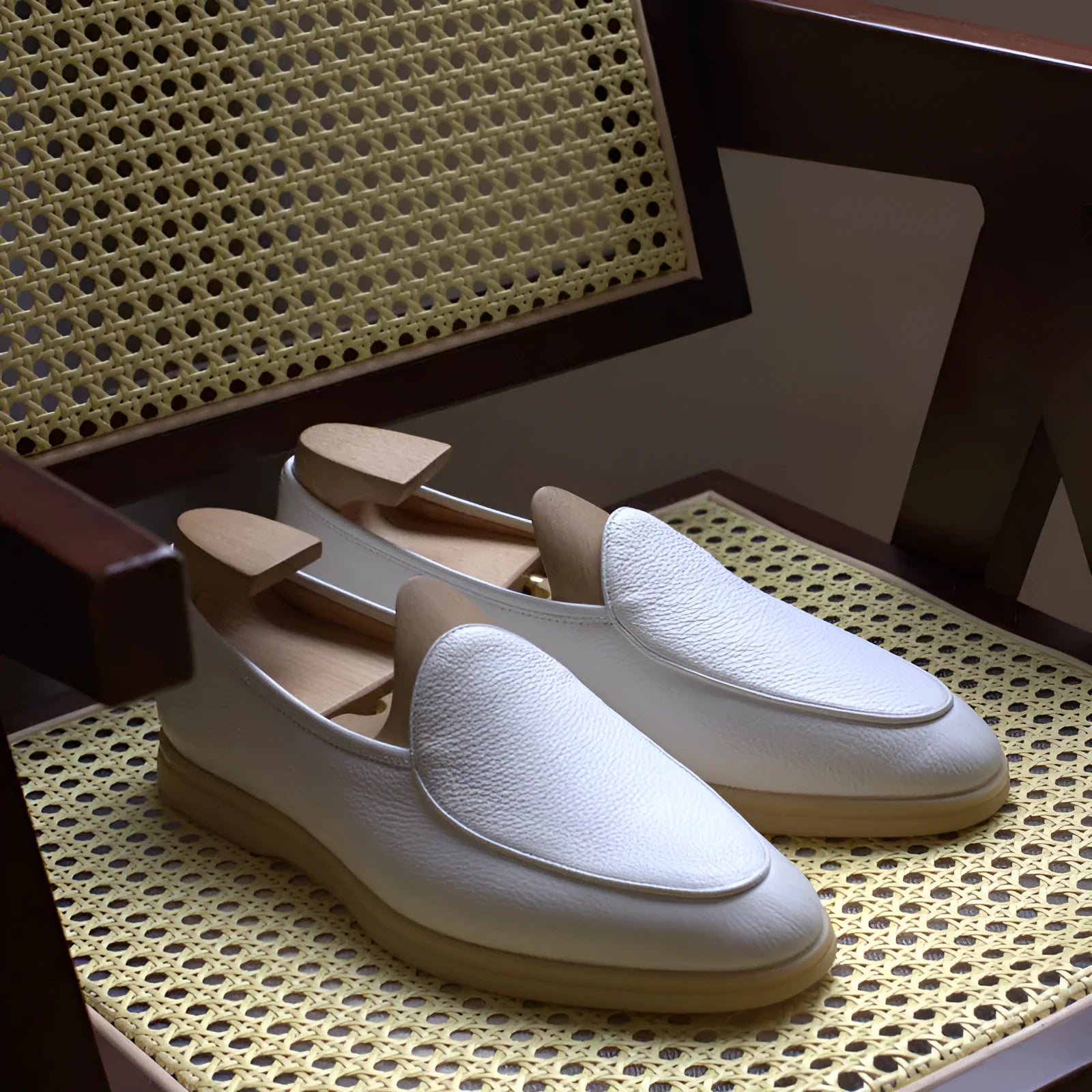 British handmade men's brown genuine leather flat loafers on a plain background.