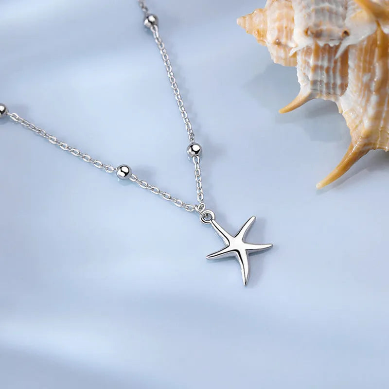 Close-up of a sterling silver starfish charm anklet with a round beaded chain.