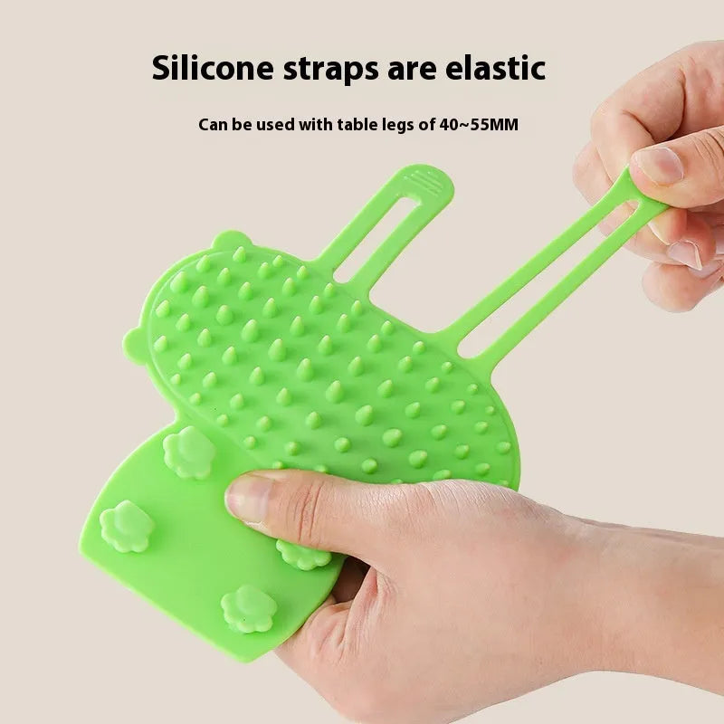 Silicone cat grooming comb scratcher with adjustable strap mounted on a table leg