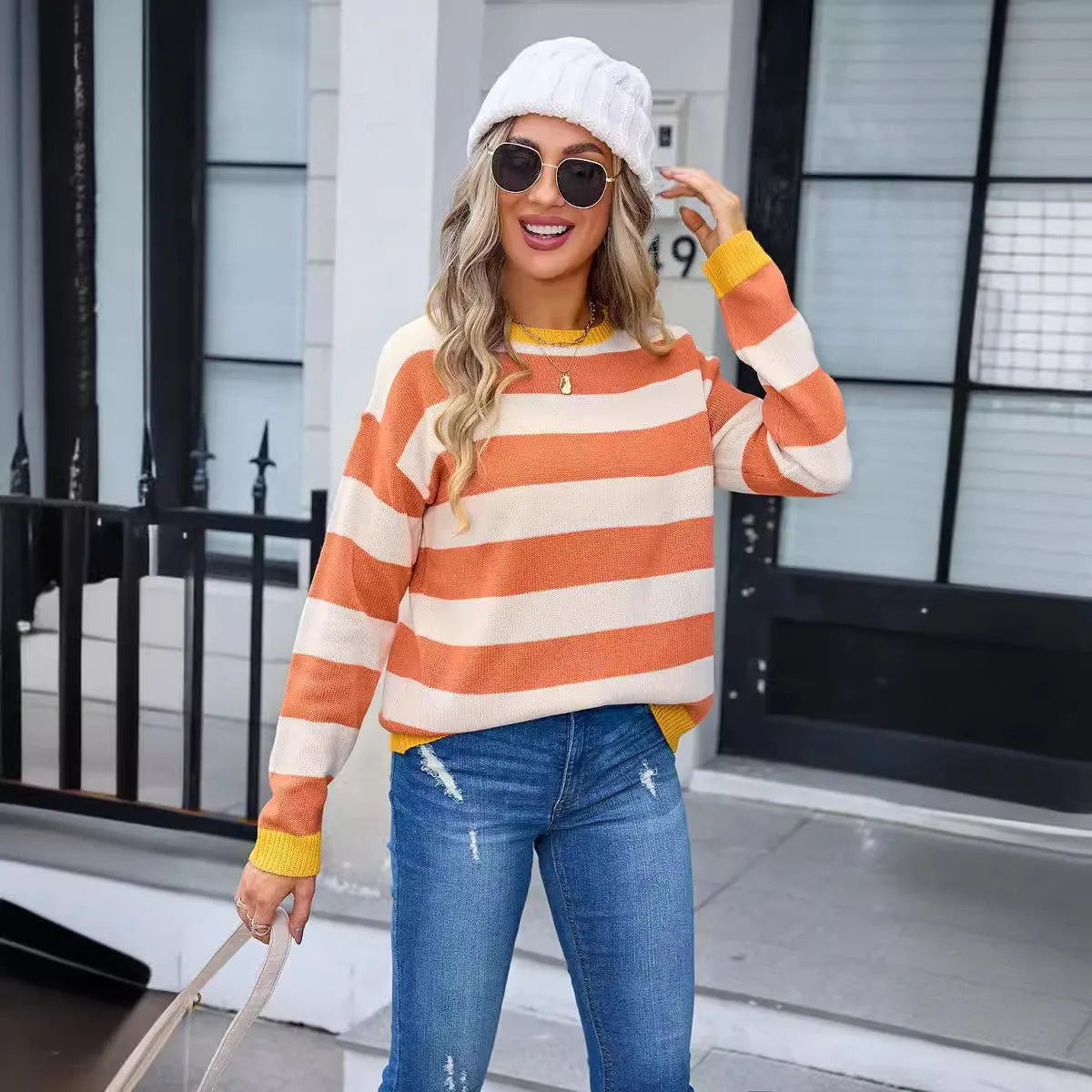 Woman wearing a loose blue and white striped acrylic sweater with long sleeves and a round neck.