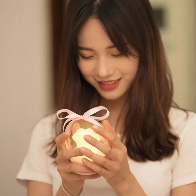 Grey and pink cat paw shaped night light with USB charging cable and musical rotation feature