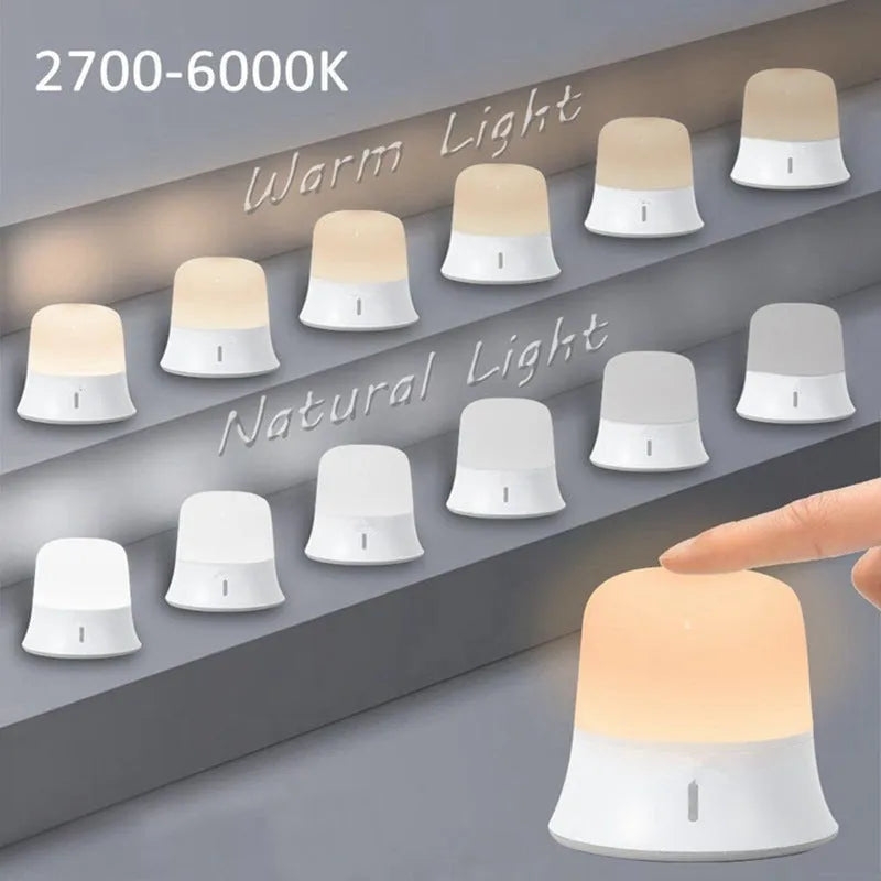 White rechargeable bedside night light with touch controls on a wooden table.