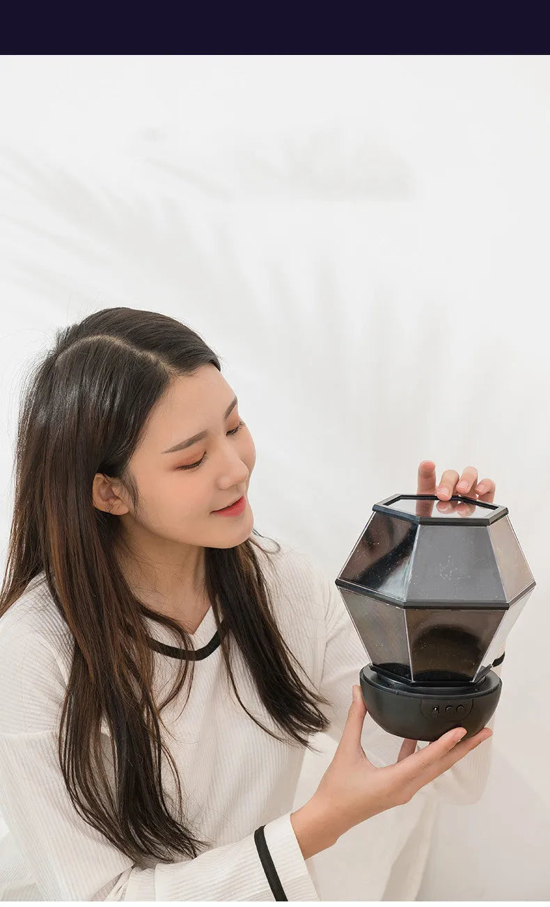Children's rotating star projector night light projecting blue and green starlight onto a bedroom wall.