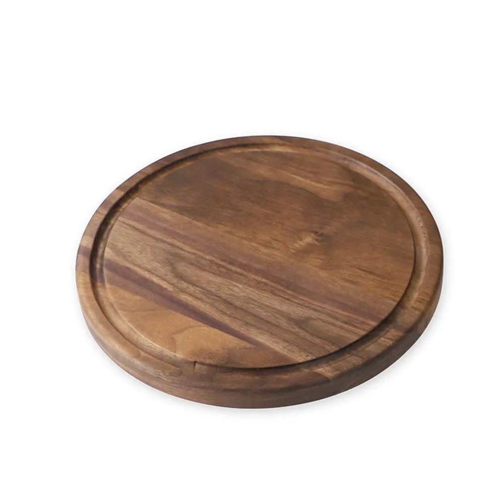Black walnut wood chopping board with juice groove and side handle on kitchen counter