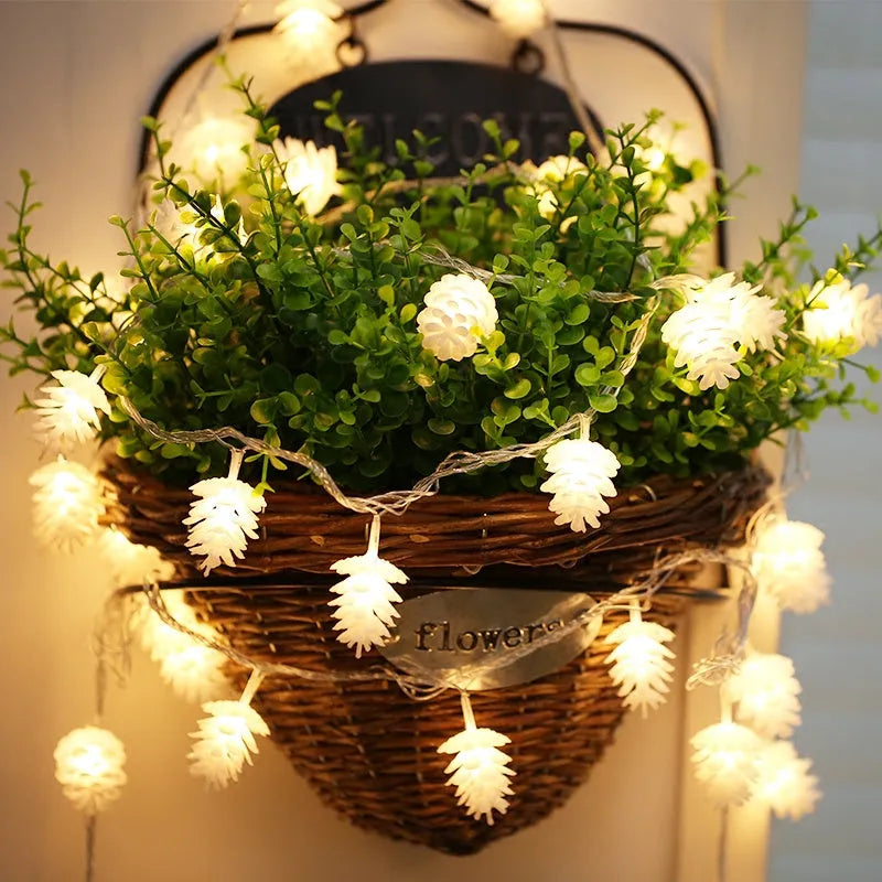 Warm white LED pine cone light string powered by AA batteries, shown in a 10-light or 20-light option for decorative use.