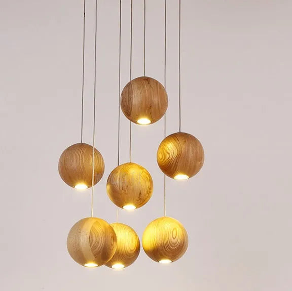 Nordic wood ball chandelier pendant light with adjustable cord, shown in a dining room setting.