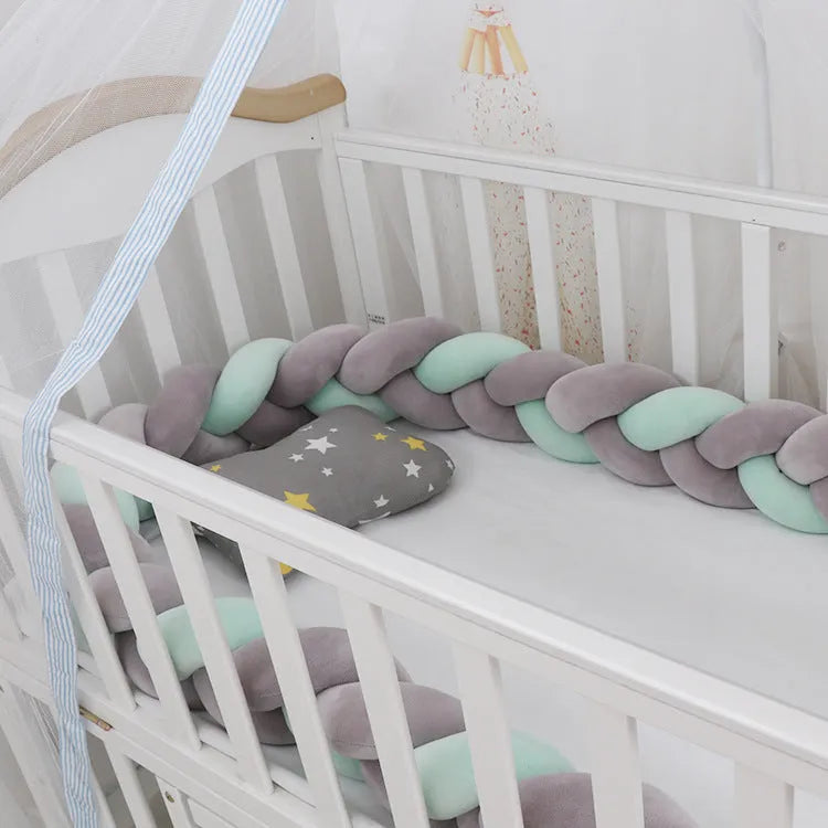 Braided knot design crib bumper in spandex velvet, shown in a light grey colour wrapped around crib slats.