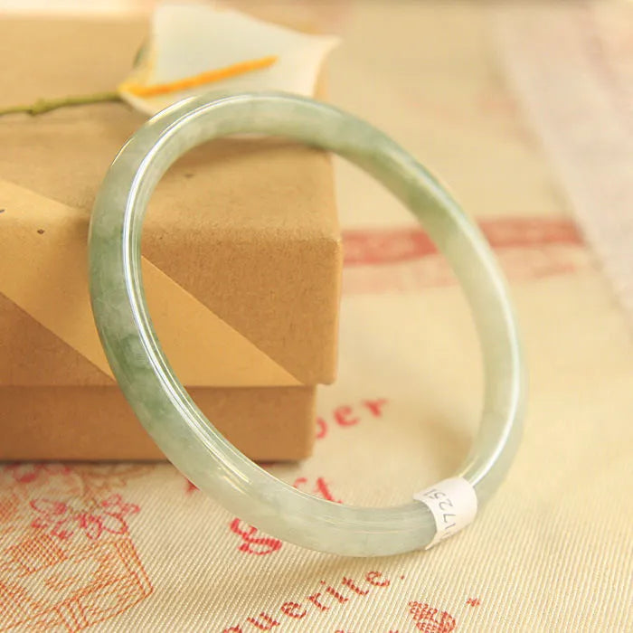 Green handmade geometric jade waxy bracelet with adjustable sizing on a wrist.